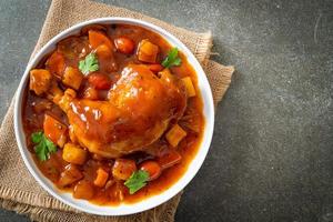 Guiso de pollo casero con tomates, cebollas, zanahorias y patatas en la placa foto