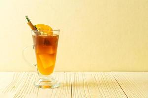 A glass of iced Americano black coffee and layer of orange and lemon juice decorated with rosemary and cinnamon photo