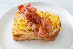 Bread toast with scramble egg and bacon on white plate photo