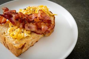 Bread toast with scramble egg and bacon on white plate photo