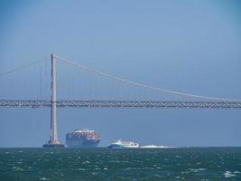 Sunny view of a cruise passing by the San Francisco Oakland Bay Bridge photo