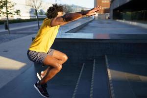 hombre negro haciendo sentadillas con saltar en un escalón. foto