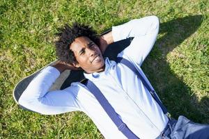 Black businessman resting lying on the grass with his skateboard photo