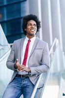 Black Businessman with afro hair standing outdoors.