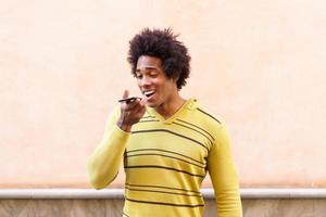 Black man with afro hair and headphones using smartphone. photo