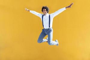 Black man with afro hair jumping on a yellow urban background photo