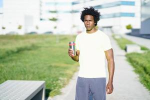 Black man drinking during exercise. Runner taking a hydration break. photo