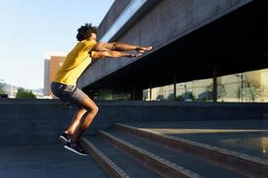 hombre negro haciendo sentadillas con saltar en un escalón. foto