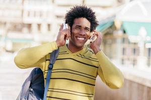 Black man listening to music with wireless headphones sightseeing