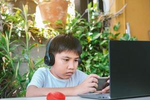 Asian boy wearing headphones playing a game on smart phone photo