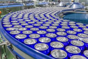 Latas en la cinta transportadora en la fábrica de bebidas. foto