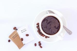 A cup of black coffee and sugar sachet photo