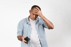 Upset man holding and looking inside his empty wallet. no money. photo