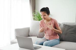 Deaf woman using laptop for video conference in sign language. photo