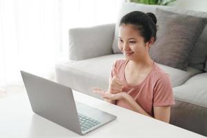 Joven mujer asiática sorda discapacitada usando laptop para videoconferencia. foto