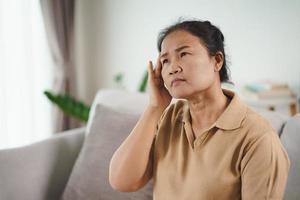 Mature senior woman suffering from headaches, Alzheimer Concept. photo