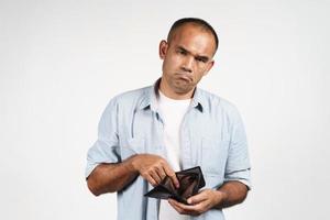 Upset man holding and looking inside his empty wallet. no money. photo