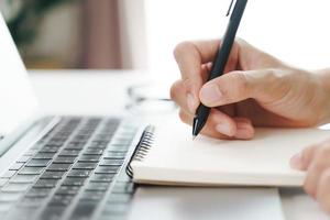 Close up of man hands writing down on the notepad, notebook using pen. photo