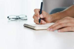 Close up of man hands writing down on the notepad, notebook using pen. photo