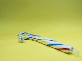 two candy colorful caramel cane on yellow background photo