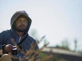 Bearded man sits and holds a camera in his hands photo