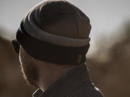 portrait of a stylish man with a beard in a knitted hat and sunglasses photo