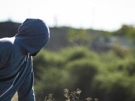 a man with a beard in the hood looks into the distance turning back photo