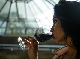 portrait of an attractive girl  who drinks red wine from a glass photo