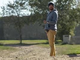 a man is standing against a background of green trees photo