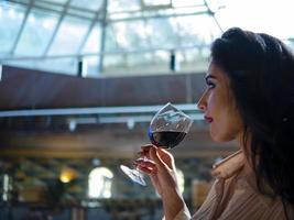 Retrato de niña morena modelo bebiendo vino tinto de una copa foto