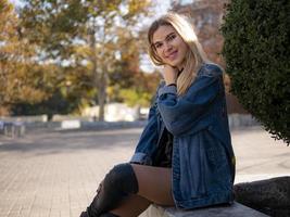 Joven rubia con un cabello hermoso sonriendo sentado al aire libre foto