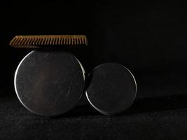 Peine de madera y frascos de cera para barba y bigote sobre un fondo negro foto