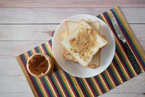 Vista superior de la mantequilla de maní y una pila de pan en la mesa foto