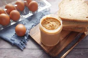 top view of peanut butter and a bread on plate on black background photo