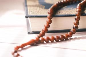 Holy book Quran and rosary on table, close up. photo