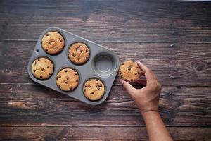 Vista superior de la mano del hombre sosteniendo la torta de la taza de chocolate en la mesa foto