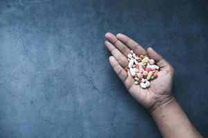 La mano del hombre con la medicina derramada fuera del contenedor de pastillas foto