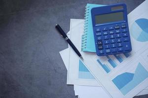 financial graph, calculator and notepad on black background photo