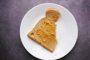 Vista superior de la mantequilla de maní y una pila de pan en la mesa foto
