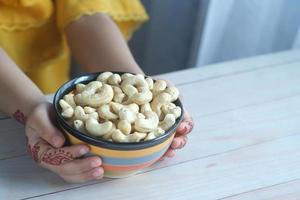 child hand hold bowl of cashew nut photo