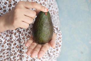 women hand hold slice of avocado with copy space photo