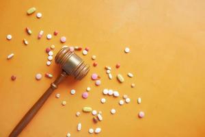 Top view of gavel, and medical pills on orange background photo