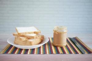 Mantequilla de maní y pila de pan en la mesa con espacio de copia foto