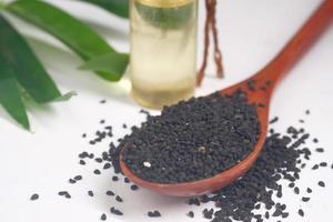 Black Cumin on spoon with oil in a jar on table. photo