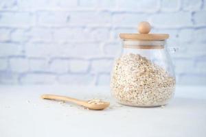 Copos de avena en un frasco con cuchara en la mesa foto