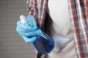 hand in blue rubber gloves holding spray bottle cleaning table photo