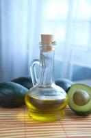 oil in glass jar and slice of avocado on wooden table photo