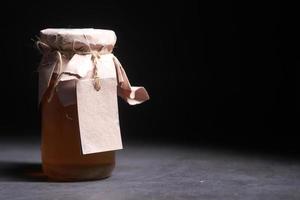 Miel fresca en un frasco de vidrio con una etiqueta vacía de papel. foto