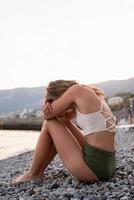 joven, mujer deprimida, sentado, en la playa foto