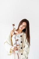 Beautiful woman in cozy clothes holding branch of cotton flowers photo